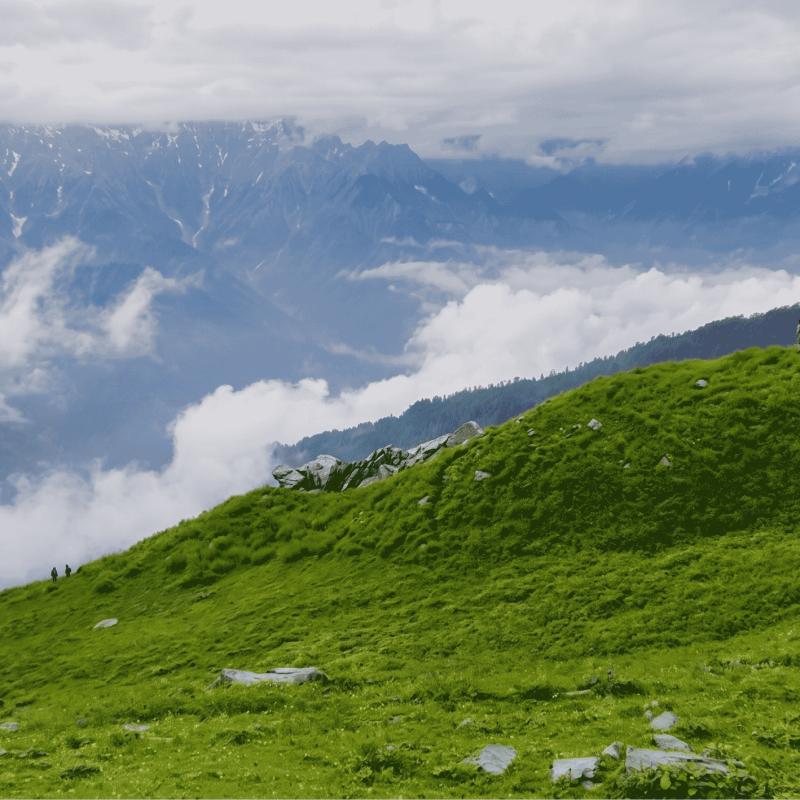 Trekkers walking on the scenic trail to Bhrigu Lake with mountain meadows